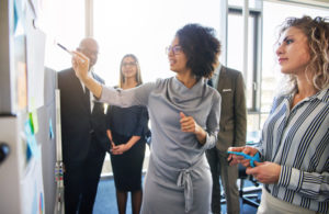 Diverse team members collaborate at whiteboard in office