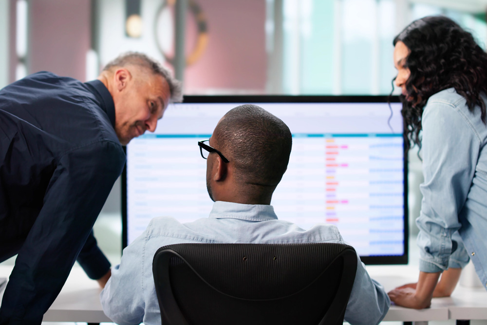Business colleagues analyze data on computer screen.